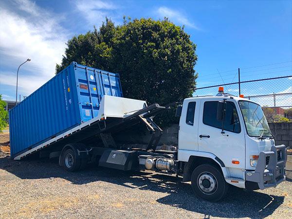 blue storage container unloading from removal vehicle